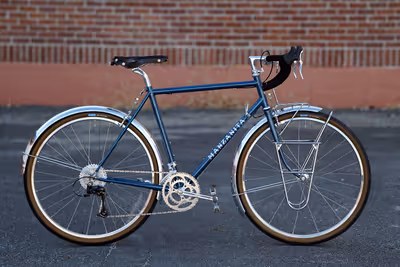 Randonneuring bike with silver fenders, custom racks, and dynamo lighting